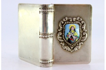 Caixa para comprimidos em prata em forma de livro com figura de Santa em esmalte na tampa.